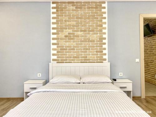 a white bed in a room with a brick wall at Аппартаменты в Центре in Poltava