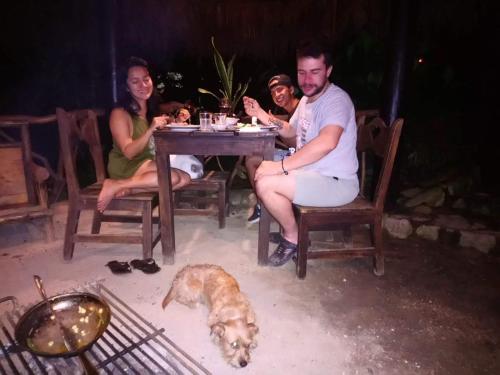 a group of people sitting at a table with a dog at Finca de la Vaca - Glamping in Palora