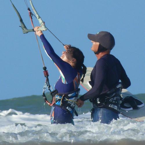 a man and woman standing in the water holding onto a kite at Pousada Casa Azul do Piauí in Luis Correia