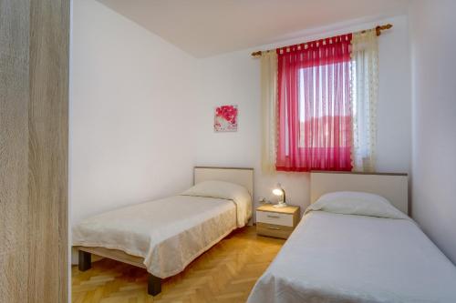 two beds in a room with a red window at Apartments with a parking space Mali Losinj (Losinj) - 7879 in Mali Lošinj