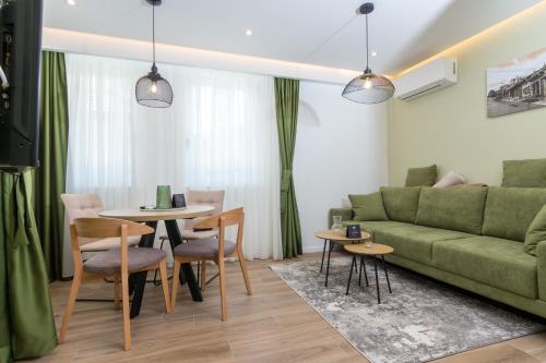 a living room with a green couch and a table and chairs at Mayisa Apartments in Sarajevo