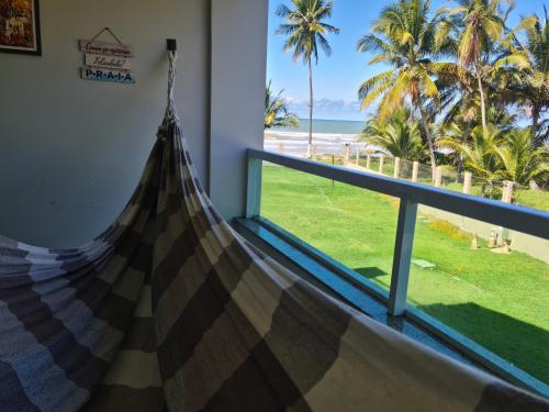 a room with a balcony with a view of the beach at APARTAMENTO À BEIRA MAR - PÉ NA AREIA - Ilhéus in Ilhéus