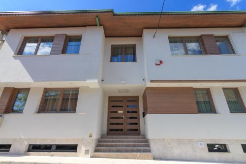 a white house with a wooden door and stairs at Mayisa Apartments in Sarajevo
