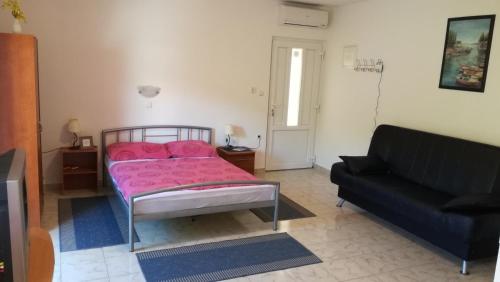 a bedroom with a pink bed and a black couch at Studio Barbat 11472a in Rab