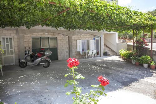 a scooter parked in front of a house with roses at Apartment Tucepi 11486a in Tučepi
