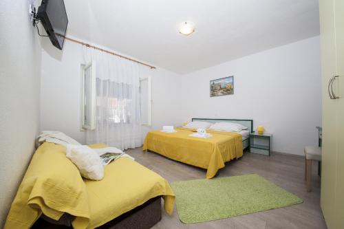 two beds in a room with yellow sheets at Apartment Tucepi 11486a in Tučepi