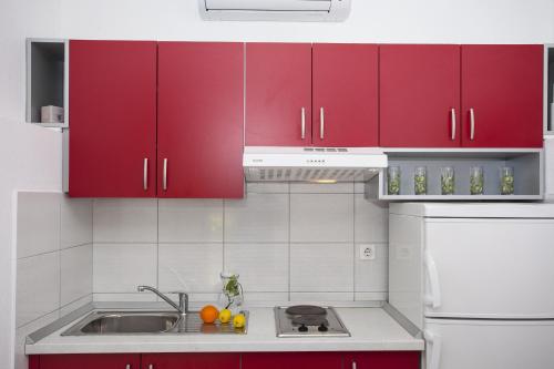 a kitchen with red cabinets and a sink at Apartment Tucepi 11486a in Tučepi