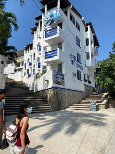 a woman wearing a mask walks in front of a building at MayFlower Hotel & Hostal in Puerto Escondido