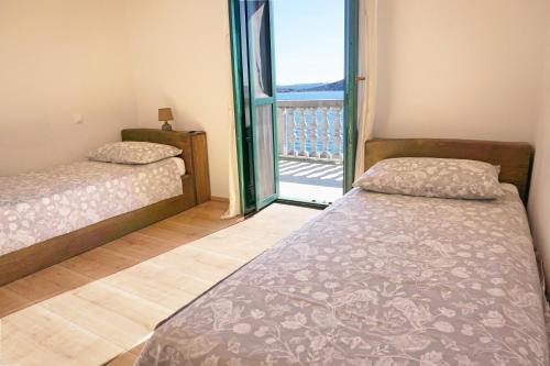 a bedroom with two beds and a balcony at Secluded fisherman's cottage Cove Donje More, Pasman - 11515 in Tkon