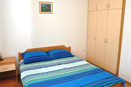 a small bedroom with a bed with blue pillows at Apartments with a parking space Selce, Crikvenica - 11527 in Selce