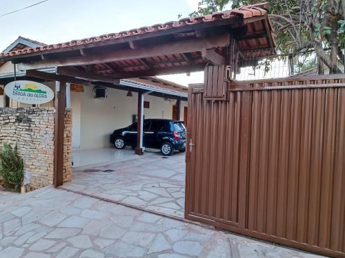 a wooden gate to a garage with a car parked at Brisa da Serra Hotel Pousada Pirenopolis in Pirenópolis