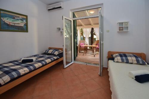 a bedroom with two beds and a door to a patio at Apartments by the sea Novalja, Pag - 11512 in Novalja