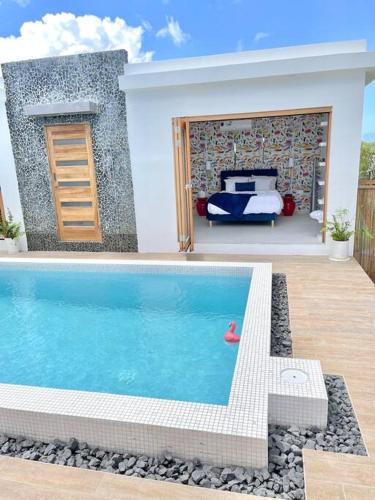 a swimming pool in front of a bedroom with a bed at Moringa Resort - Studio B with Pool, open Air Shared Shower Bath in Willemstad