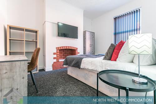 een slaapkamer met een bed en een tafel en een televisie bij Severn Street House Serviced Accommodation in Leigh