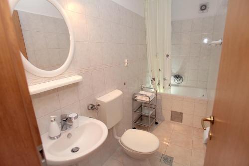 ein Badezimmer mit Toilette, Waschbecken und Spiegel in der Unterkunft Apartments with a parking space Mavarstica, Ciovo - 11563 in Trogir