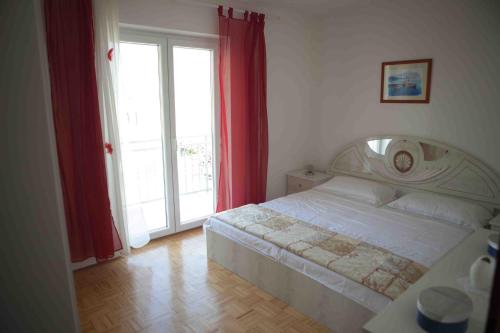 sypialnia z dużym łóżkiem z czerwonymi zasłonami w obiekcie Apartments by the sea Suhi Potok, Omis - 11574 w mieście Jesenice