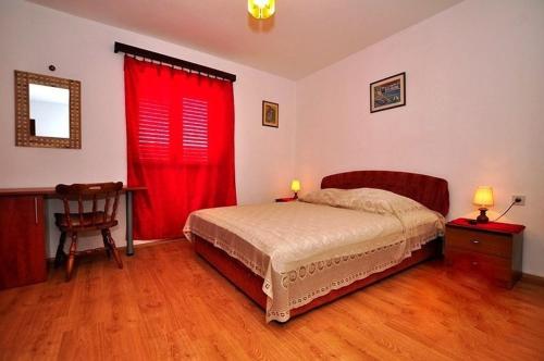 a bedroom with a bed with a red curtain at Apartments by the sea Slatine, Ciovo - 11565 in Slatine