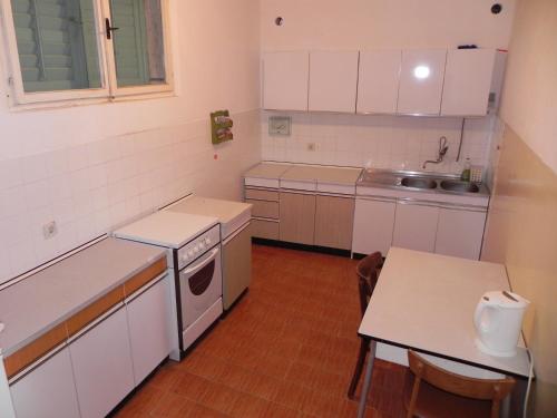 cocina con armarios blancos, mesa y fregadero en Apartment Sveta Nedilja 11433c en Sveta Nedelja