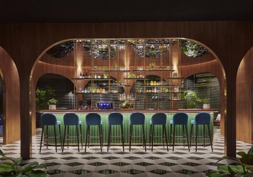 a bar with blue chairs in front of a counter at PARKROYAL COLLECTION Kuala Lumpur in Kuala Lumpur
