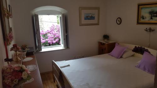 a bedroom with a bed and a window with purple pillows at Apartments with a parking space Jelsa, Hvar - 13759 in Jelsa