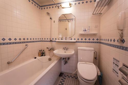 a bathroom with a toilet and a sink and a tub at Hotel Monterey Osaka in Osaka