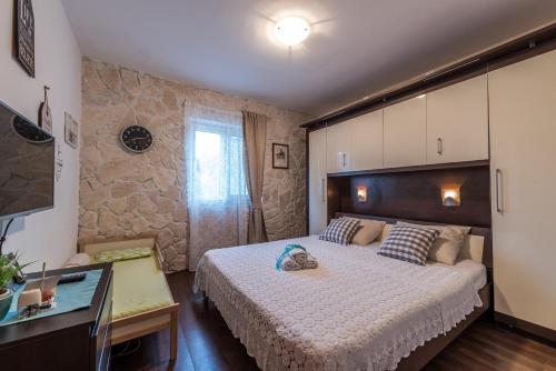 a bedroom with a large bed and a stone wall at Family friendly apartments with a swimming pool Sutomiscica, Ugljan - 13872 in Preko