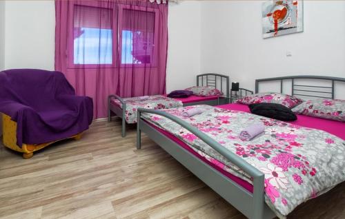sypialnia z 2 łóżkami i fioletowym krzesłem w obiekcie Seaside apartments with a swimming pool Krilo Jesenice, Omis - 13898 w mieście Jesenice