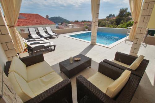 eine Terrasse mit Stühlen und einem Pool in der Unterkunft Family friendly house with a swimming pool Brna, Korcula - 13943 in Smokvica
