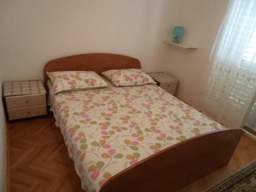 a small bedroom with a bed with a floral comforter at Apartments and rooms with parking space Makarska - 13979 in Makarska