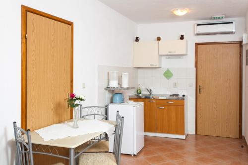 a small kitchen with a table and a white refrigerator at Apartments and rooms by the sea Lopud, Elafiti - 14013 in Lopud Island