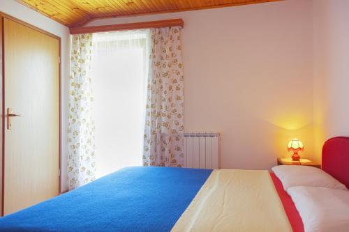 a bedroom with a blue and white bed and a window at Double Room Smoljanac 14023b in Smoljanac