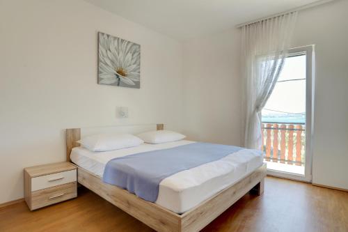 a bedroom with a bed and a window with a balcony at Family friendly apartments with a swimming pool Kastel Sucurac, Kastela - 14047 in Kaštela