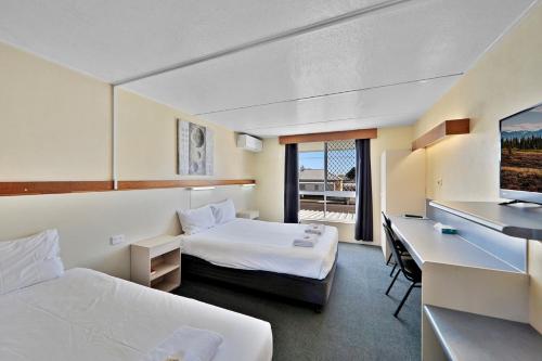 Habitación de hotel con 2 camas y escritorio en Oscar Motel en Bundaberg