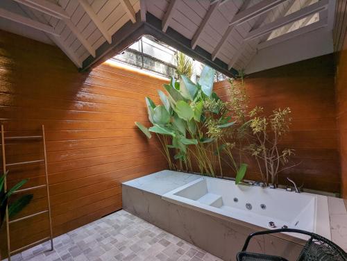 a bathroom with a tub with plants on the wall at Cottonwood Boutique Heritage Otten in Bandung