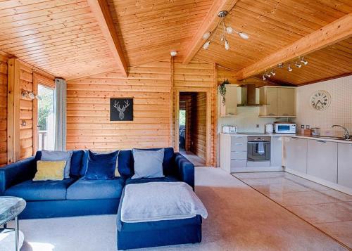a living room with a blue couch and a kitchen at Fingle Glen Lodges in Whitestone