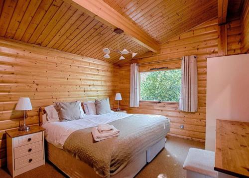 a bedroom with a bed in a log cabin at Fingle Glen Lodges in Whitestone