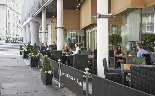 a group of people sitting at tables outside a building at Thistle Trafalgar - Leicester Square in London