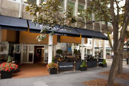 a building with a restaurant with tables and flowers at Thistle Trafalgar - Leicester Square in London