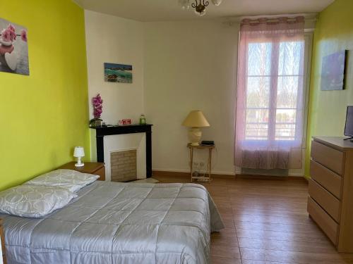 Un dormitorio con una cama y un televisor y una ventana. en Chez Virginie, en Gisors