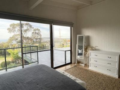 a bedroom with a bed and a large glass window at Family Beach Home Dromana in Dromana