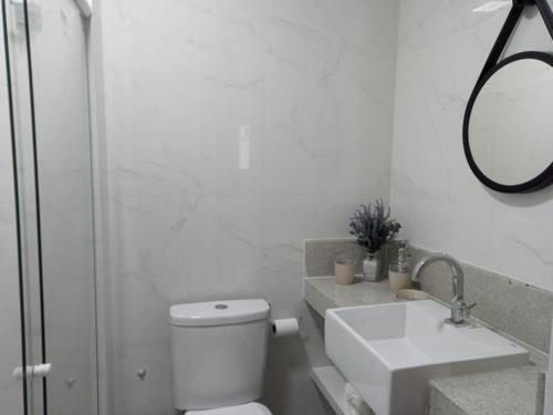 ein Badezimmer mit einem WC, einem Waschbecken und einem Spiegel in der Unterkunft Lindo AP na Praia da Costa melhor bairro da cidade in Vila Velha