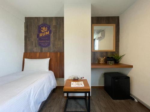 a bedroom with a bed and a table and a mirror at Roaders Hotel Hualien Dongda in Hualien City