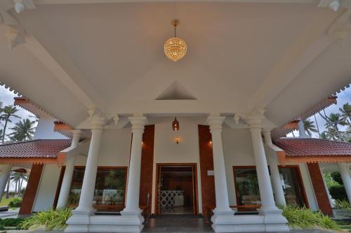 a large white building with columns and a door at Lagoona Beach Resort in Kovalam