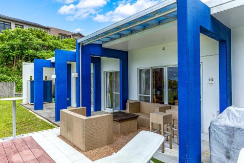 ein Haus mit blauen Säulen und einer Terrasse in der Unterkunft Hermit Hills Okinawa  -SEVEN Hotels and Resorts- in Onna