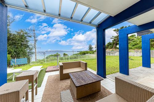 een patio met een tafel en stoelen en uitzicht op de oceaan bij Hermit Hills Okinawa  -SEVEN Hotels and Resorts- in Onna