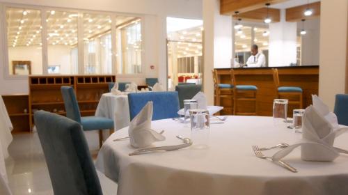 une salle à manger avec des tables et des chaises avec un homme en arrière-plan dans l'établissement Hotel Delphin-Nouadhibou, à Nouadhibou