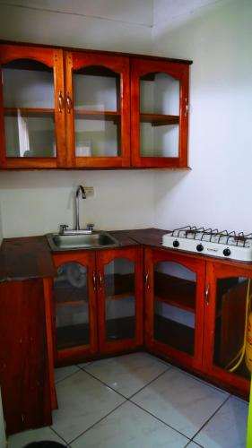 a kitchen with a sink and a stove and cabinets at Hotel Restaurante Los Cocos in Santa Cruz