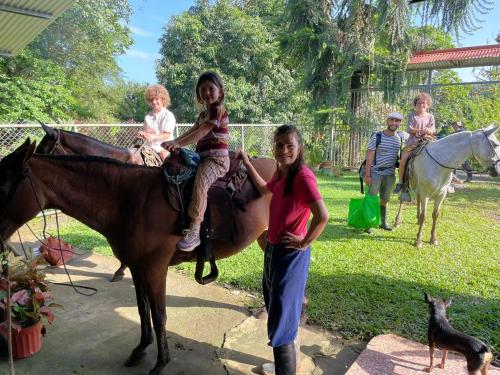 dos niños están sentados en un caballo con una mujer en Oasis del Tortuguero en Cariari