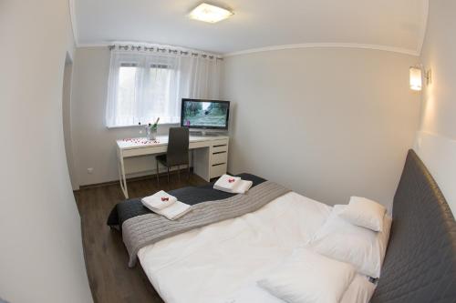 Schlafzimmer mit einem Bett und einem Schreibtisch mit einem Computer in der Unterkunft Apartament Lazur in Piła