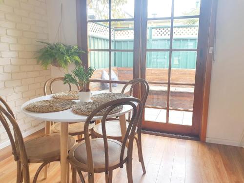 a dining room table with chairs and a plant on it at Olive Street Apartment in Albury